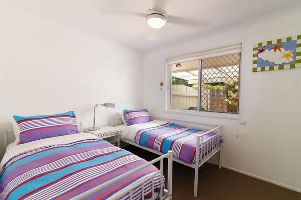 Twin bedroom with mirrored built-ins, fly screen, view to pool, blackout blinds