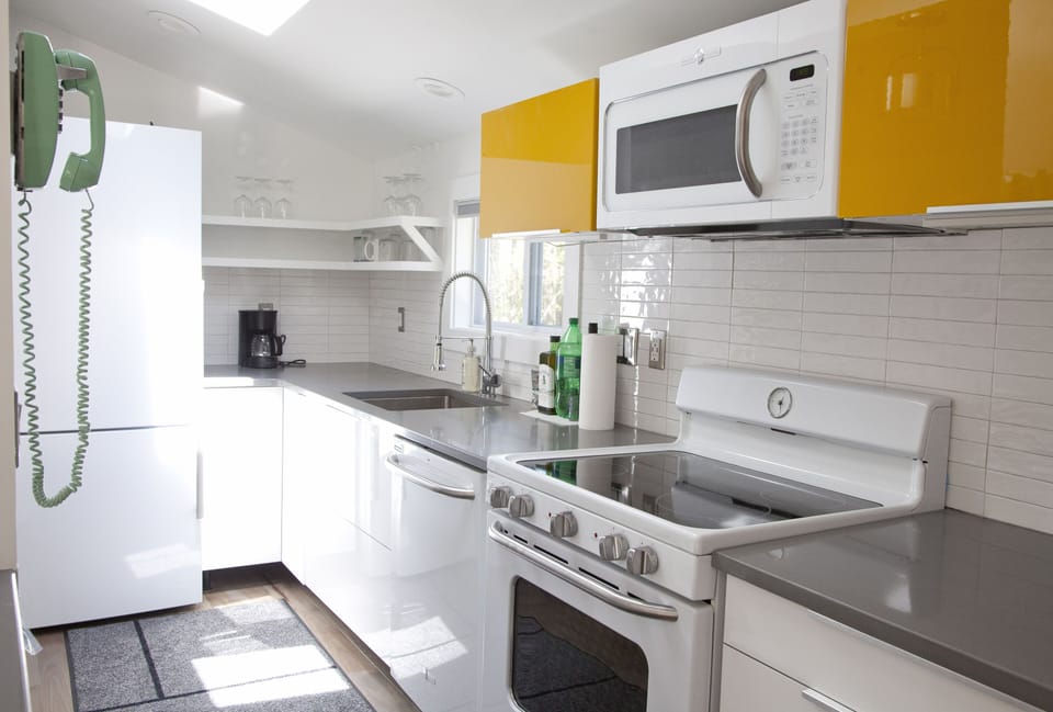 Full kitchen features quartz counter top, range vent sucks air outside. 