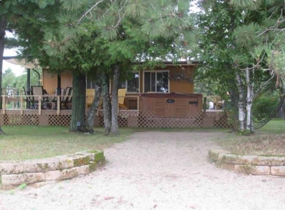 The deck off of the cabin with a hot tub, BBQ gas grill and a shaded eating area