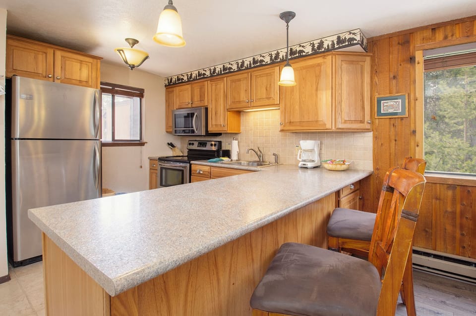 Cook memorable meals in your fully equipped kitchen, featuring granite counters, stainless appliances, and warm wood cabinetry with mountain views.