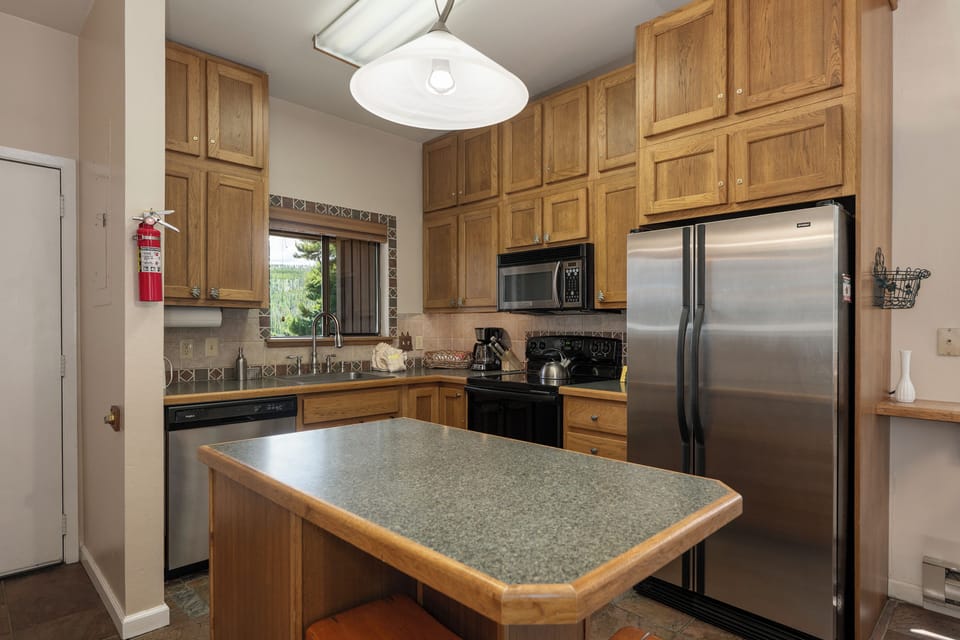 Your fully-equipped kitchen awaits with warm wood cabinetry, granite countertops, and stainless steel appliances for creating memorable vacation meals.