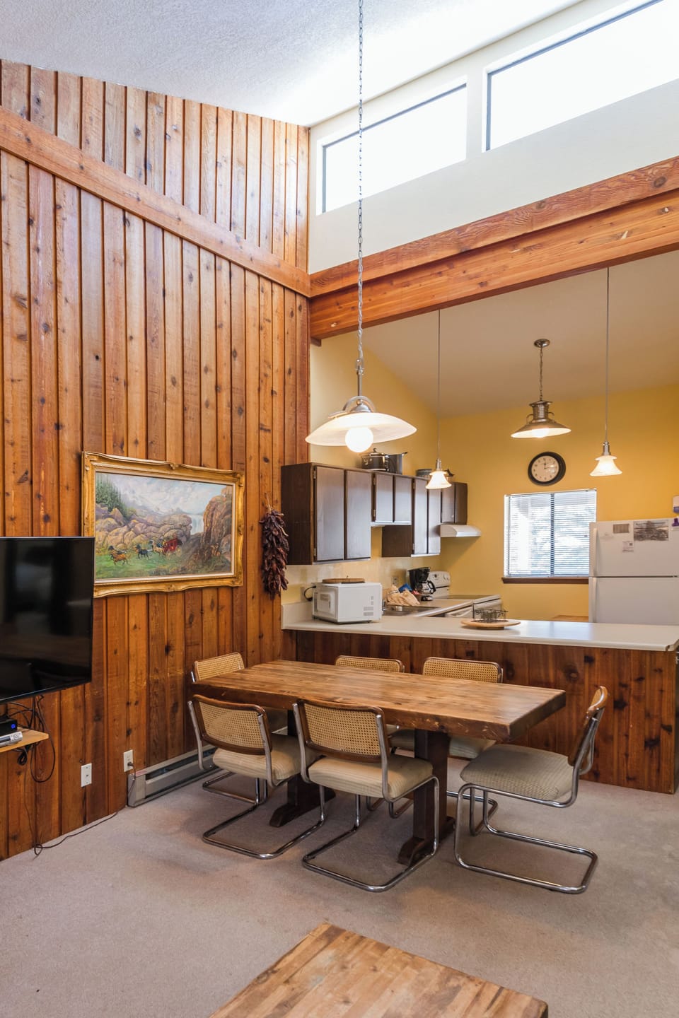 Your rustic retreat features rich wood paneling, a spacious dining table, and modern kitchen—perfect for gathering with loved ones.