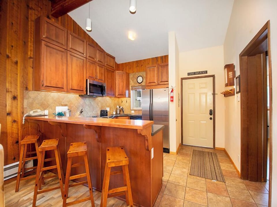 Your fully-equipped kitchen features warm wood cabinets, granite countertops, and modern appliances, with a breakfast bar perfect for morning coffee.