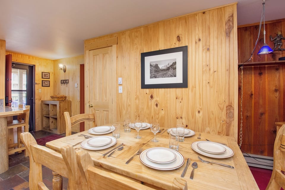 Gather around your rustic wooden dining table for memorable meals in this cozy pine-paneled space, complete with elegant place settings.