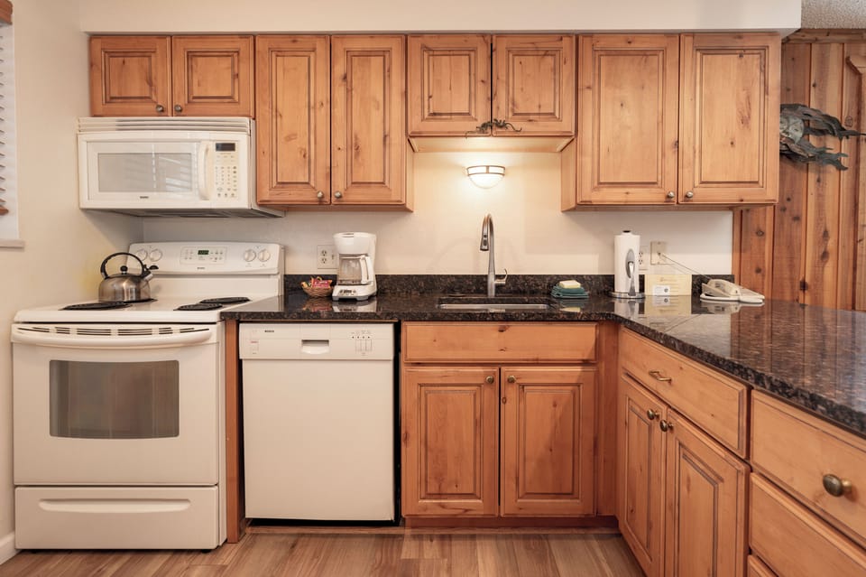 Your fully equipped kitchen features warm wood cabinets, granite counters, and all modern appliances for preparing memorable meals during your stay.