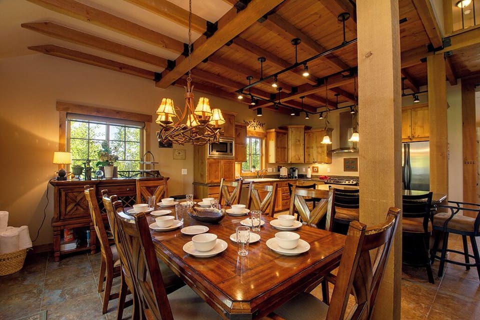 Gather around this stunning rustic dining table where warm wood beams frame memorable meals and the open kitchen invites culinary adventures.