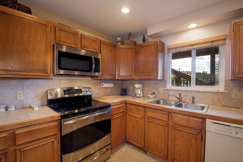 Cook your favorite meals in this fully equipped kitchen with modern appliances and warm wood cabinetry creating a cozy mountain atmosphere.