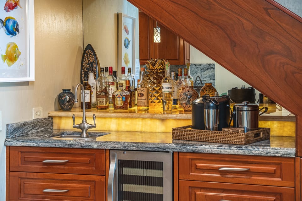 The wet bar features a bar sink, beverage fridge and cocktail utensils. 