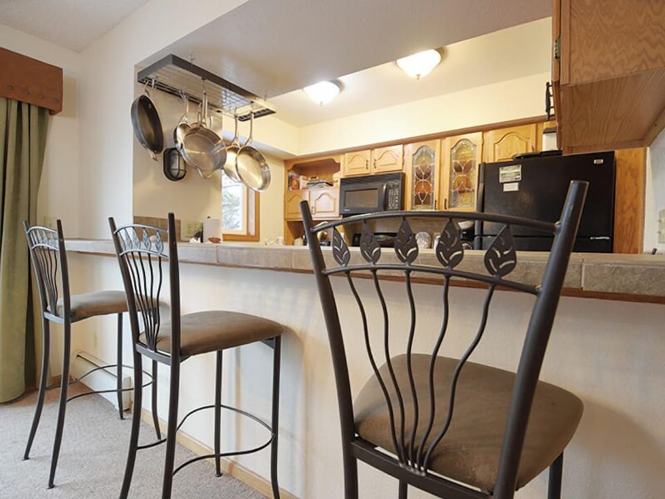 Gather around this bright kitchen island where hanging pots and warm wood cabinets create your perfect cooking space.
