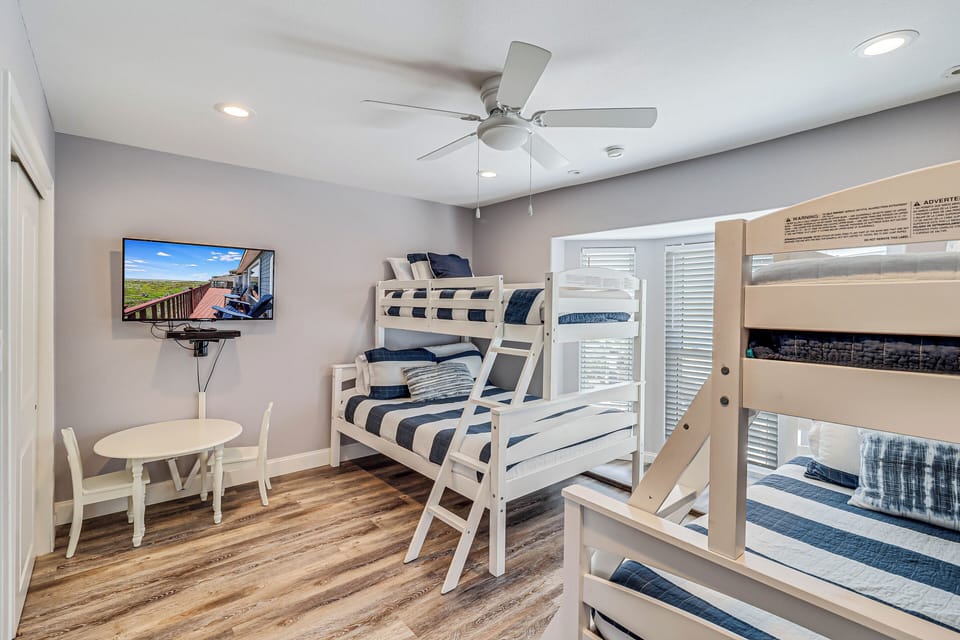 Your spacious bunk room sleeps everyone comfortably with crisp linens, entertainment, and natural light streaming through shuttered windows.