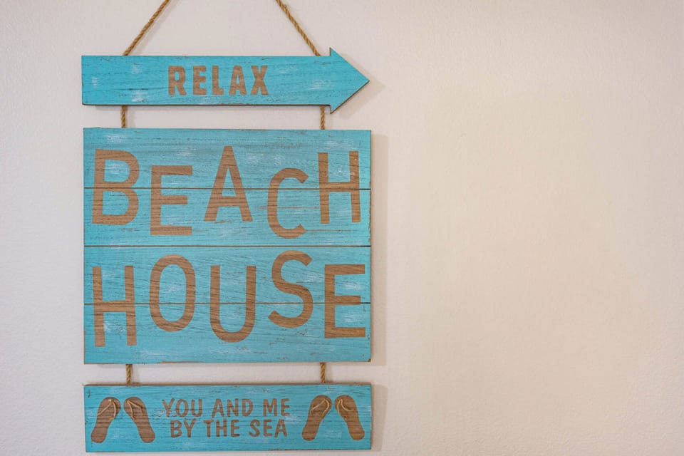 This charming beach house sign in vibrant blue adds a cheerful touch, inviting guests to relax and enjoy their stay