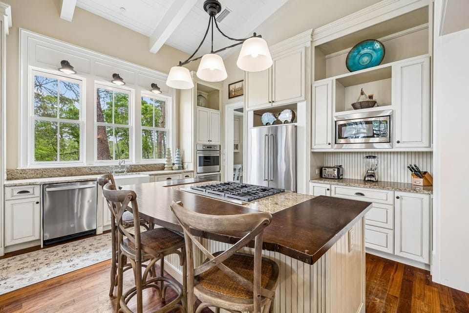Your fully equipped gourmet kitchen features granite counters, stainless appliances, a gas range island, and bright windows overlooking tranquil wooded views—perfect for cooking and gathering.