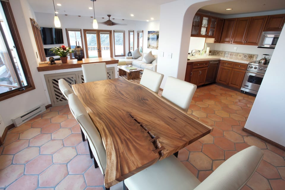 - Whip up your favorite meals in a full kitchen with rich wood cabinetry and tiled backsplash
- Artisan crafted dining table, perfect for cozy breakfasts or sunset dinners
- Open floor plan flows seamlessly to a sunlit lounge with ocean facing windows