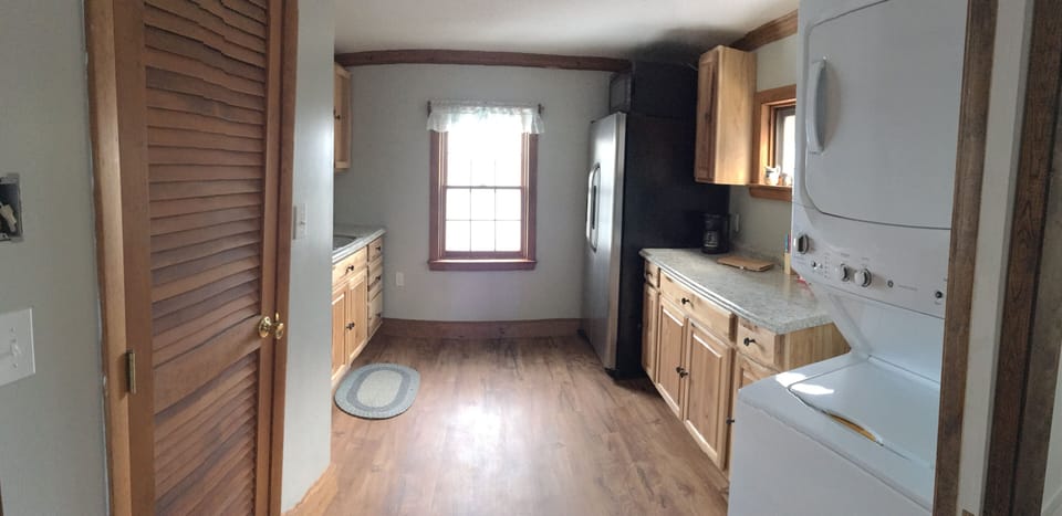 Sink, stacked washer and dryer, microwave and toaster oven. Window water view.