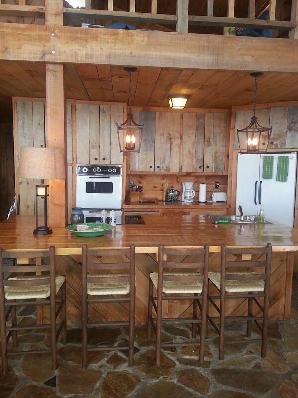 Large wooden kitchen island, rock flooring, new flat top electric stove.