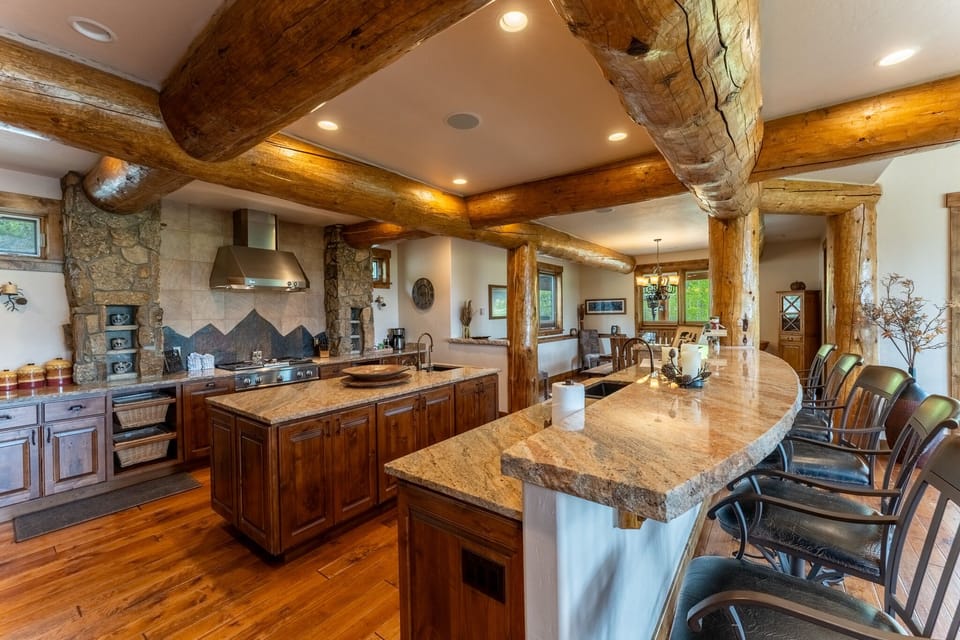 Gather around your granite island in this stunning log beam kitchen, where rustic charm meets modern convenience for unforgettable cooking experiences.