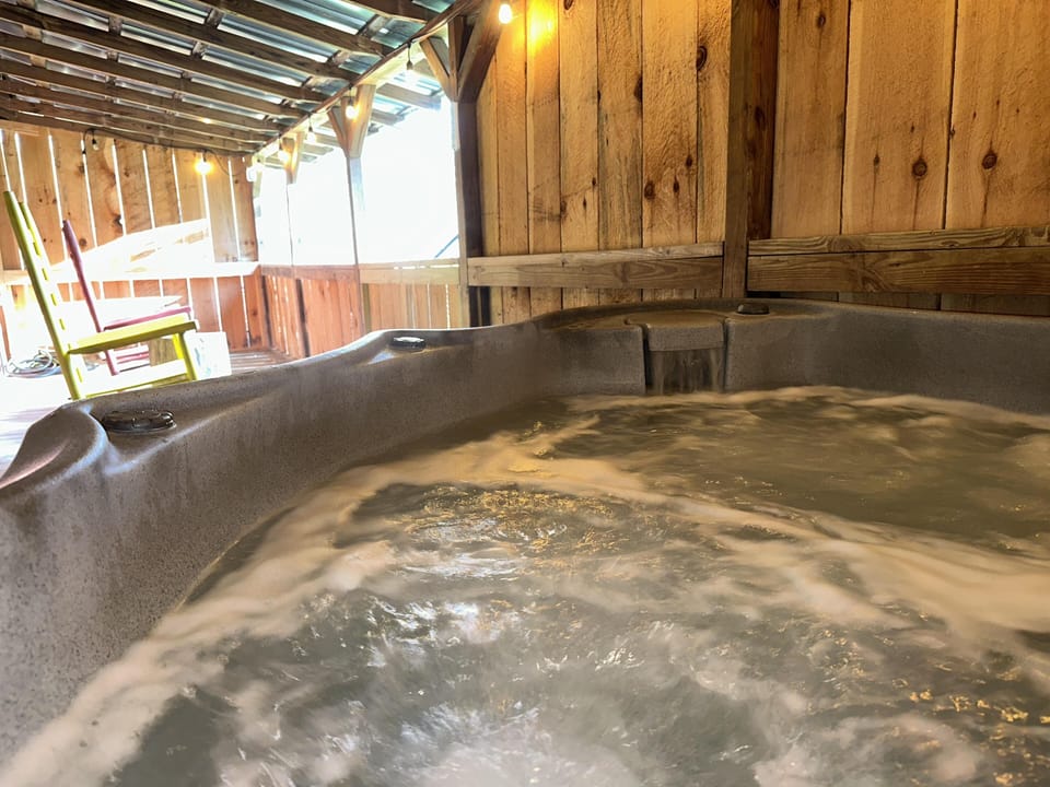 Relax in the bubbling outdoor hot tub under a cozy wooden canopy