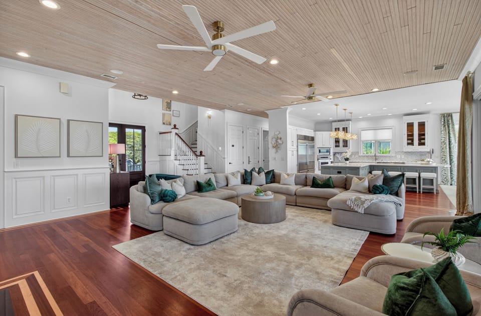 Sink into plush sectional seating surrounded by coastal elegance, where rich hardwood floors and soaring wood ceilings create your perfect gathering space.