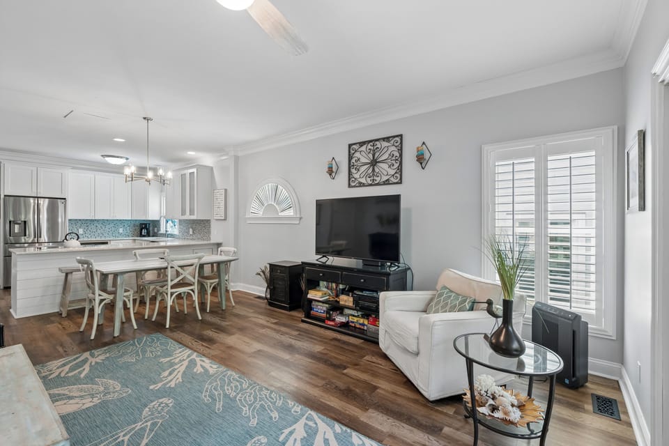 Unwind in your open-concept living space, where coastal accents meet modern comfort. Enjoy movie nights by the flatscreen, cook in your fully equipped kitchen, and dine together at the welcoming table—your perfect home base.