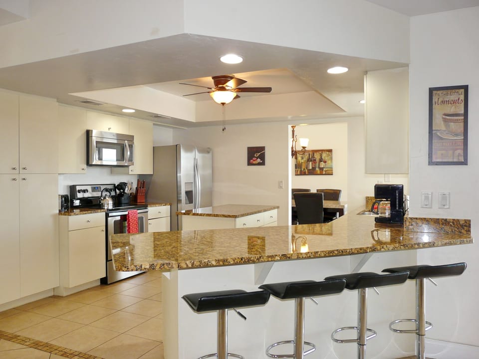 Granite countertop kitchen with island, all stainless steel appliances.