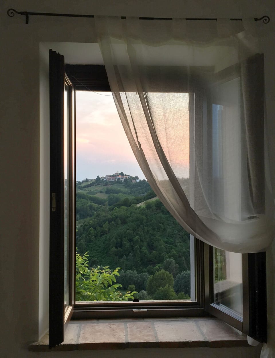 The window of the bedroom with a romantic view over the hills of Monferrato