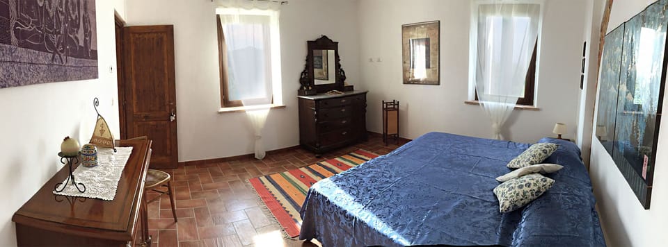 Wide view of the bedroom with the king size bed and the antique furniture