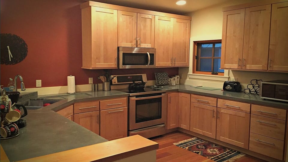Kitchen area fully equipped, stainless steel appliances, concrete countertop.
