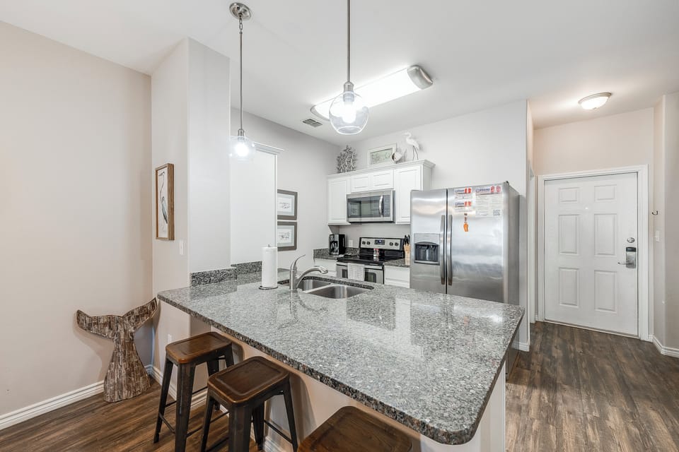 Your fully equipped kitchen features granite countertops, stainless steel appliances, and a breakfast bar perfect for morning coffee or casual dining.