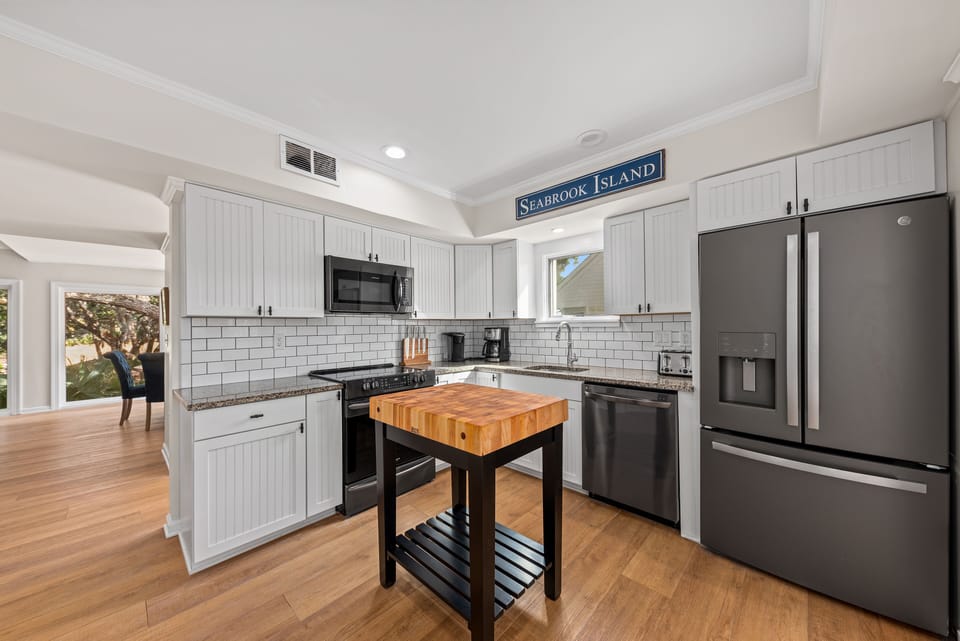 The renovated kitchen has bead board cupboards and stainless steel appliances.