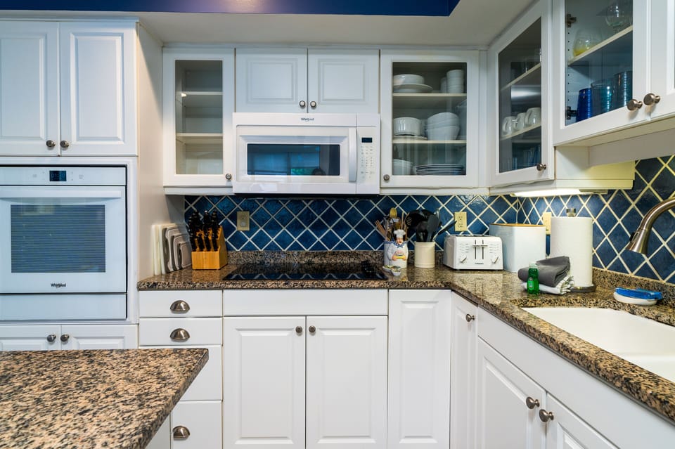 The kitchen features white cabinets, tile, and granite counters.