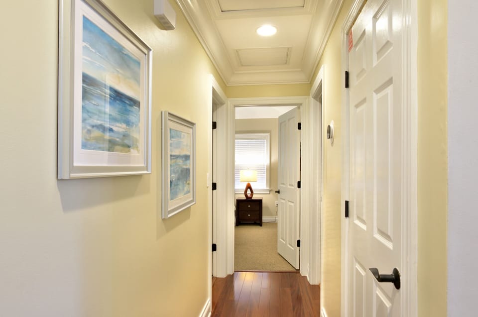 Top floor hallway - The middle room is the door on the left. The door at the end is to the 3rd bedroom with two twin beds and the door on the right leads to the hallway/shared bathroom.