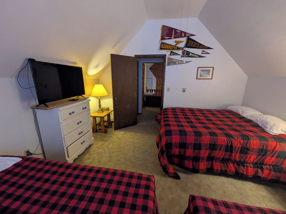 3rd floor bedroom w/ 38" smart TV, looking towards door (& 3rd fl. loft & sauna)