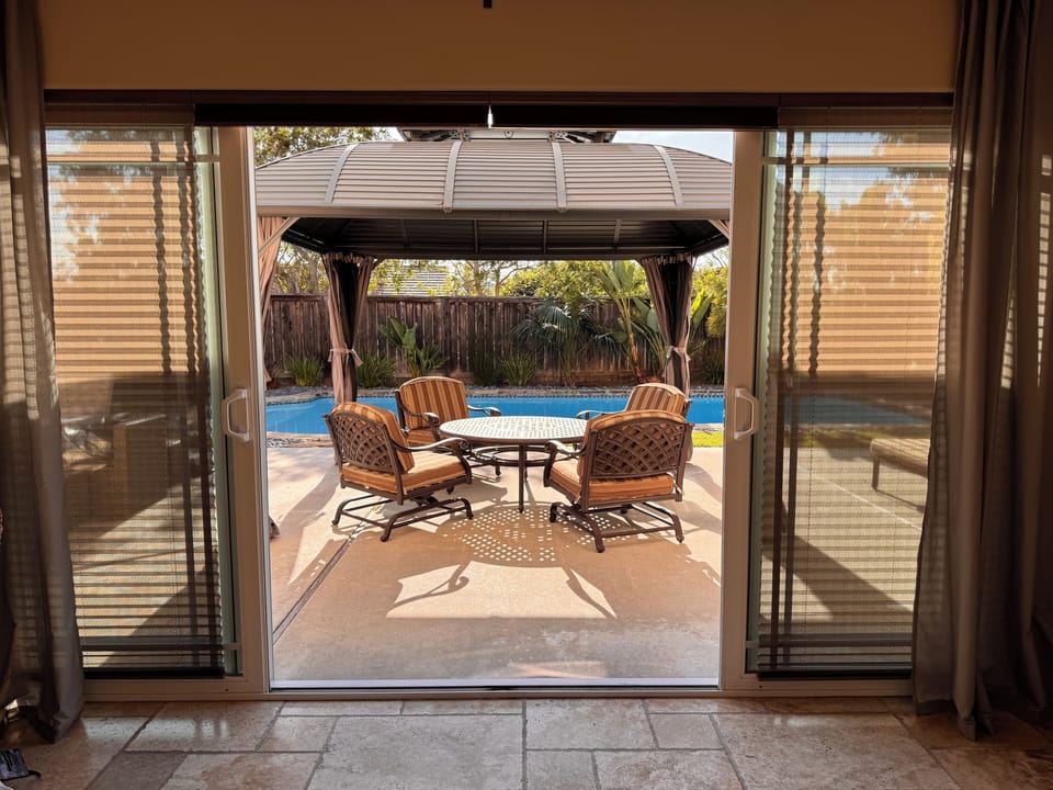 Gazebo with mosquito net and solid curtains, round table, and comfortable chairs