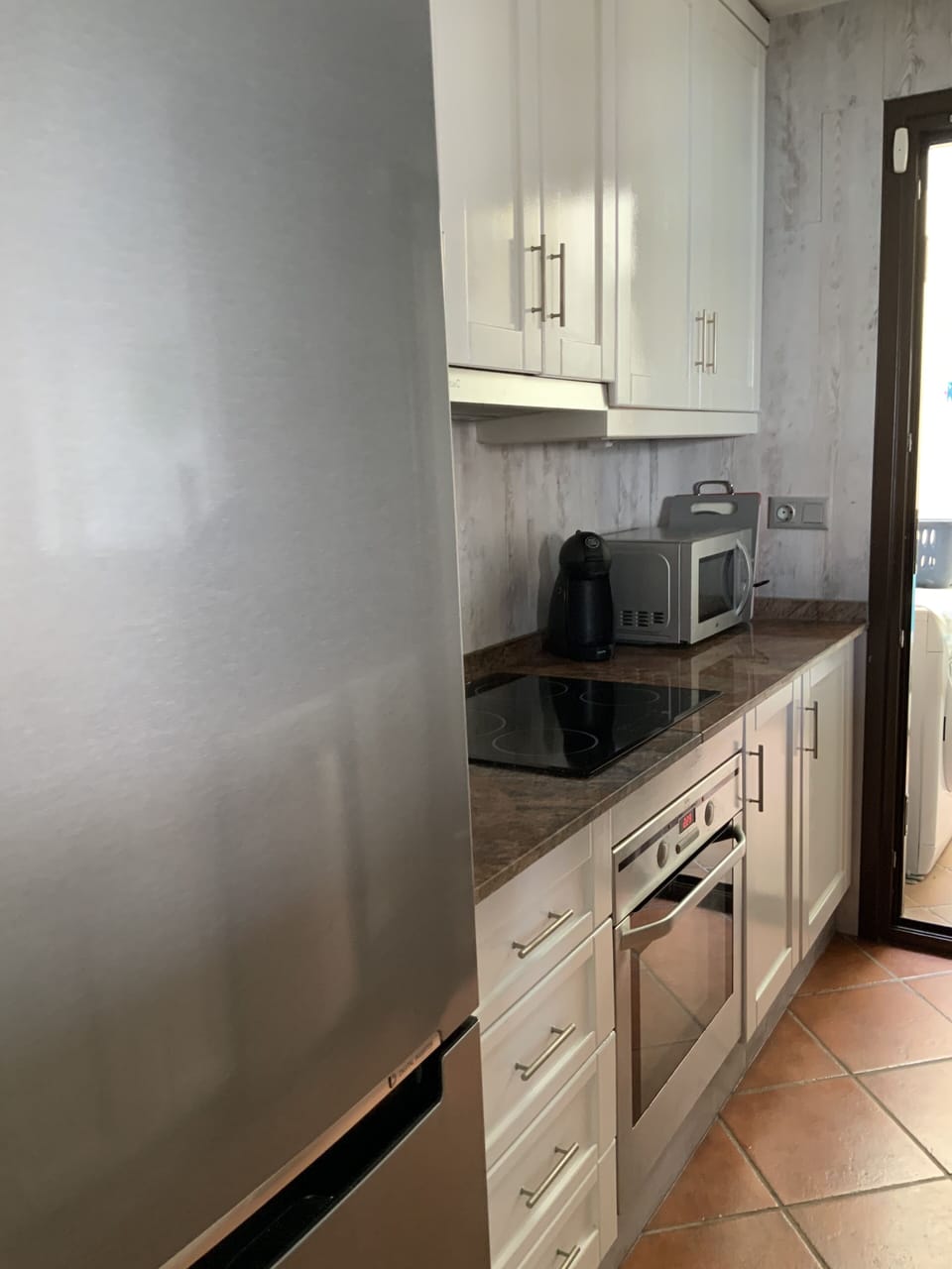 at the rear of the kitchen is a drying area and washing machine