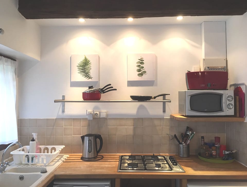 Kitchen with gas hob, microwave, washing machine, toaster, coffee machine.
