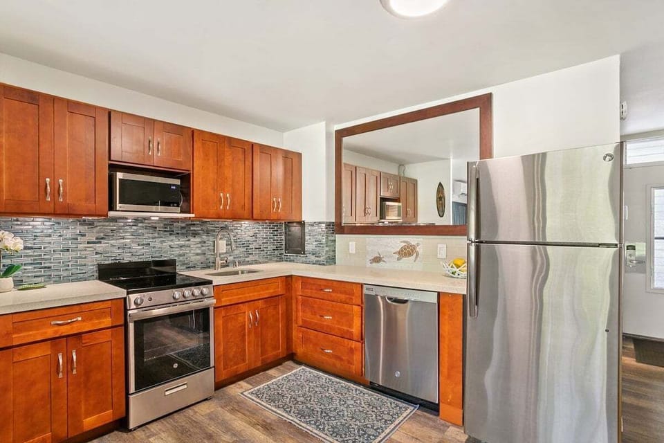 A fully updated kitchen featuring warm wood cabinetry, stainless steel appliances, and a stylish tiled backsplash.