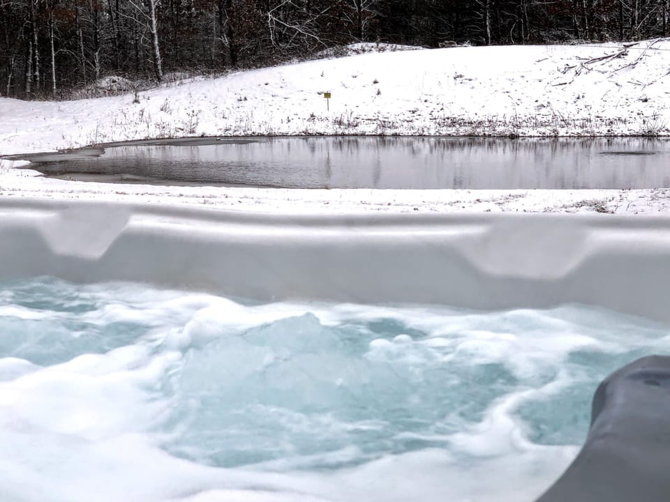 Hot tub in the winter with pond views.