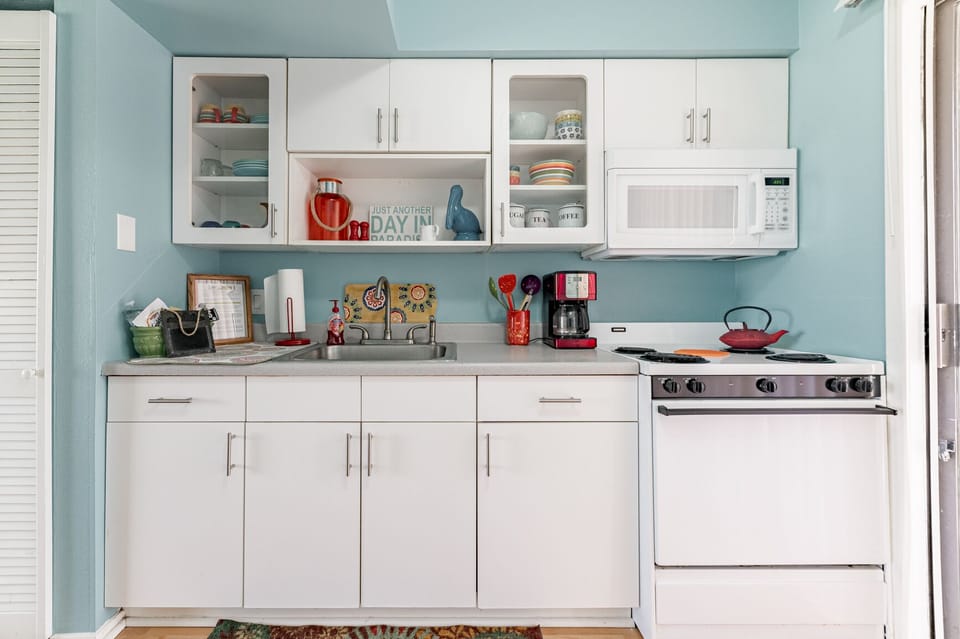 Colorful dishes, nice cookware, stove, oven, microwave, coffee maker & fridge.