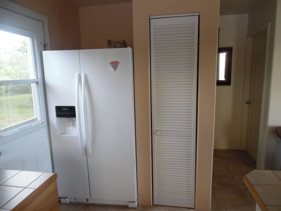 Fridge with ice maker. 
Right rear of photo is bed room door