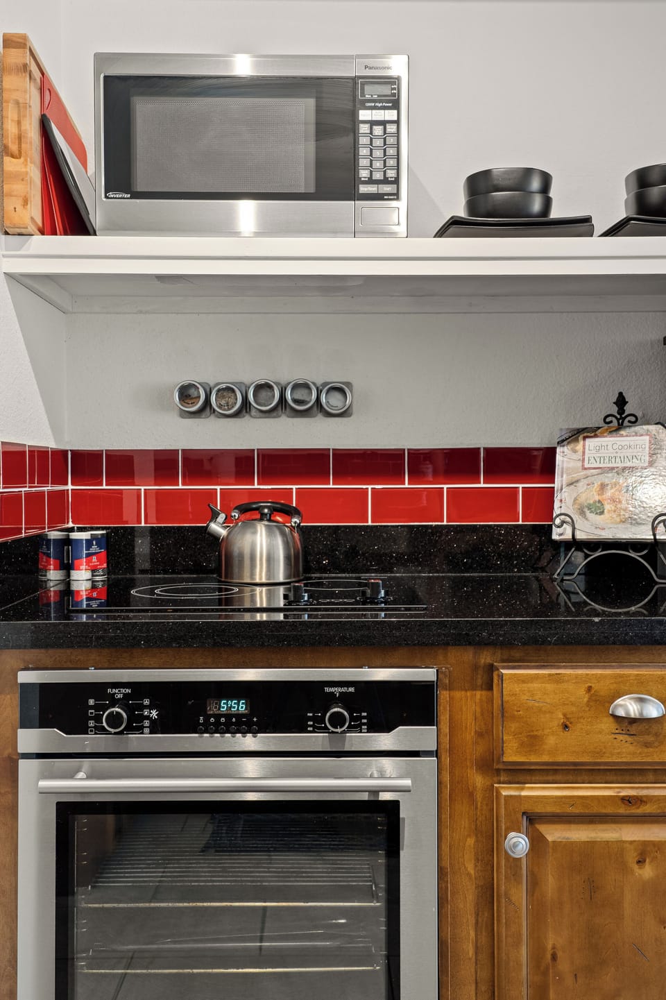 Kitchen detail: induction cooktop, wall oven, full spice rack.