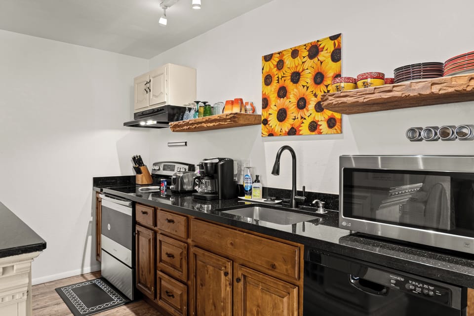 Kitchen with granite, open shelves, stocked Keurig coffee bar.
