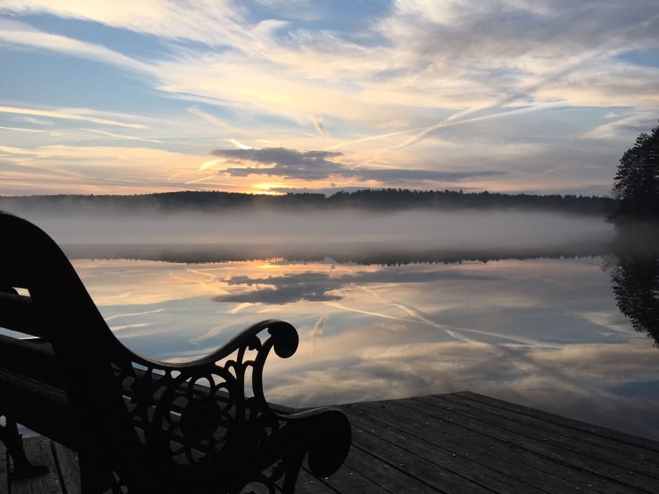 Painted sky reflects off the pond with mist over the early winter ice.