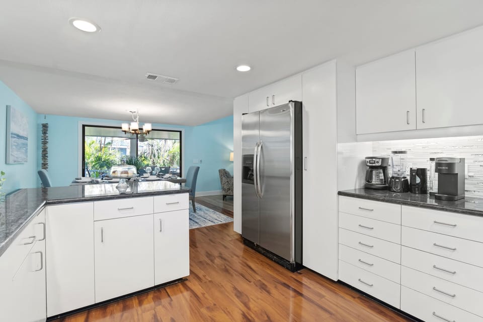 Kitchen with modern appliances and ample work space.  Dining area in background with sliding door to balcony.