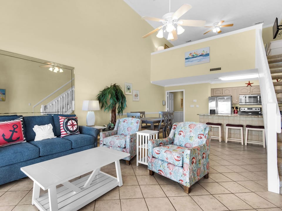 Relax in your coastal-themed living space with cozy seating, coastal decor, and open kitchen—perfect for beachside getaways.