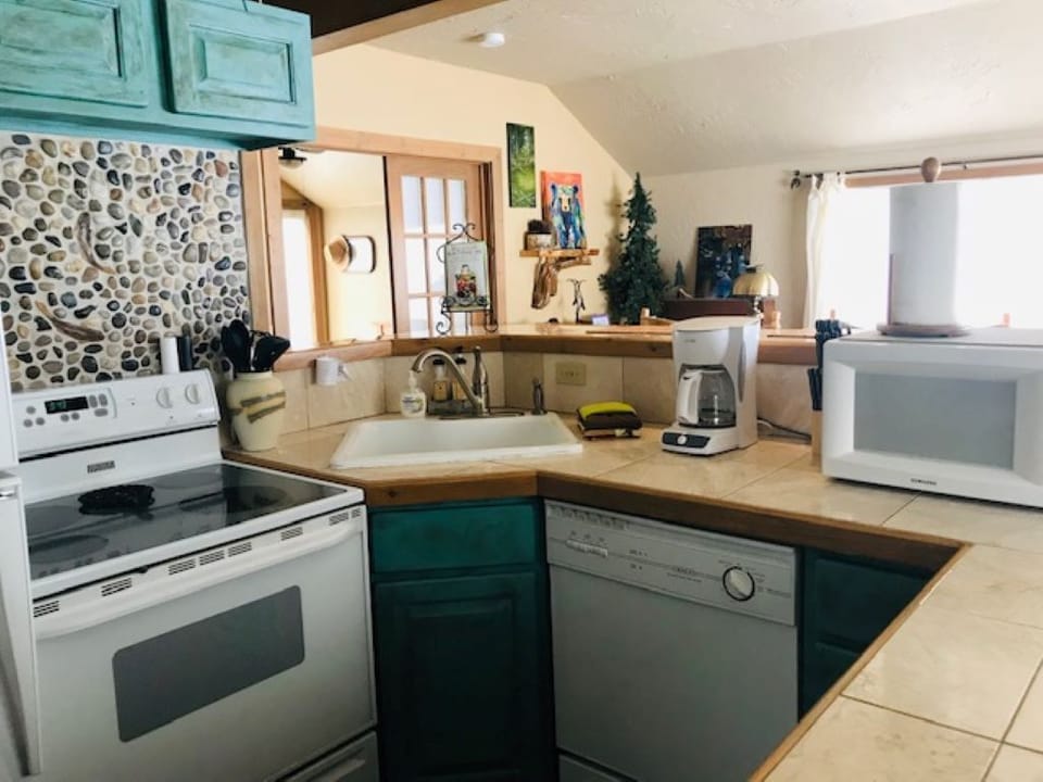 Kitchen area with bar has full fridge, microwave, coffee maker, dishwasher