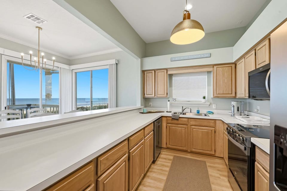 Bright, open kitchen with breakfast bar seating and beautiful ocean views—perfect for gathering, dining, and making vacation memories