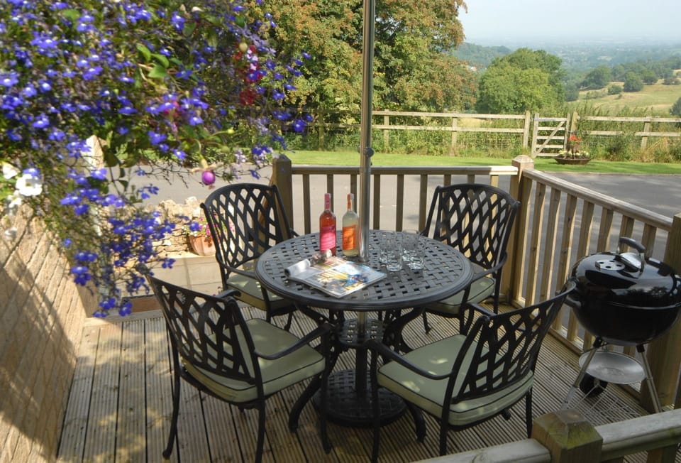 Elevated decking area with seating for four, parasol and a charcoal barbecue