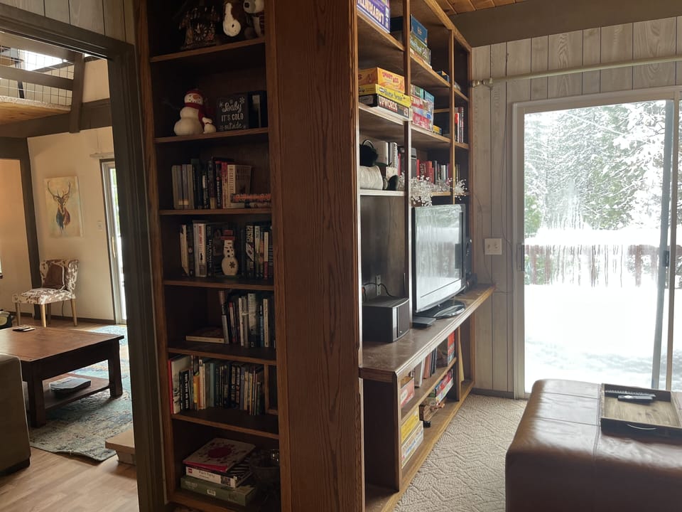 Library in game room stocked with books, board games, puzzles and streaming TV.