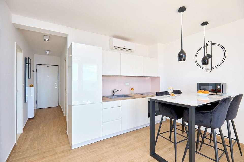 Step into a bright, modern space where a sleek kitchenette and stylish dining area welcome you with a clean, contemporary design.