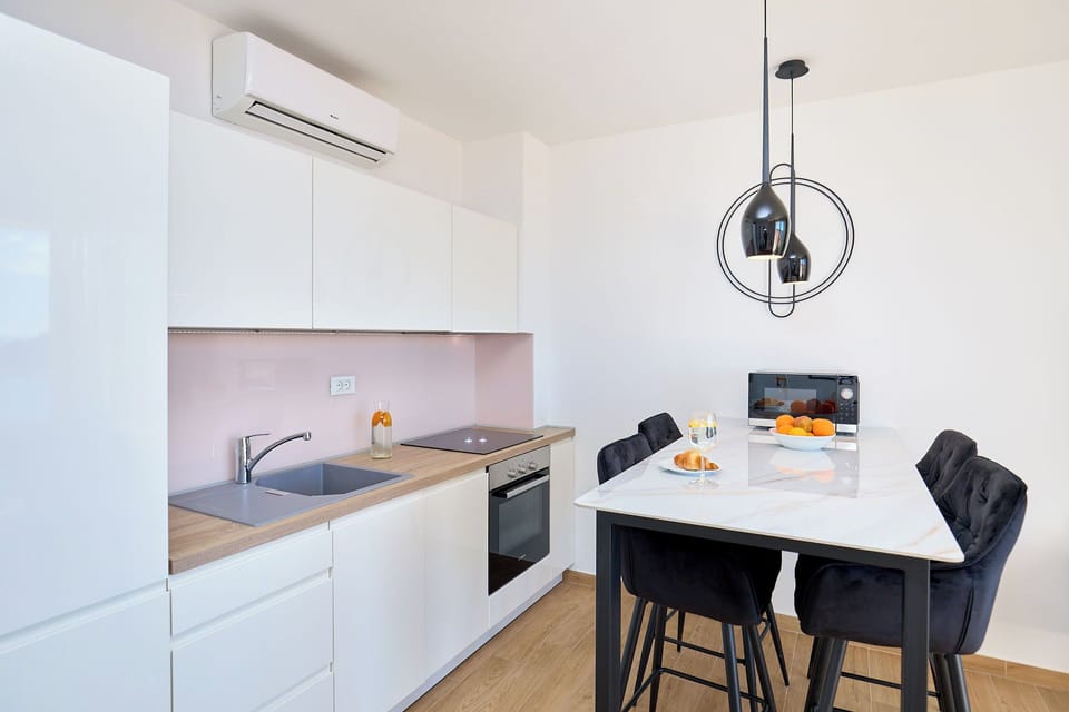 The bright, open-plan living area features a modern, fully equipped kitchen and a chic dining space, perfect for enjoying a meal.